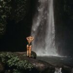 Caves And Waterfalls - Woman in Black Swimwear Standing on Rock in Front of Waterfalls