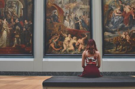 Museum - Woman Sitting on Ottoman in Front of Three Paintings